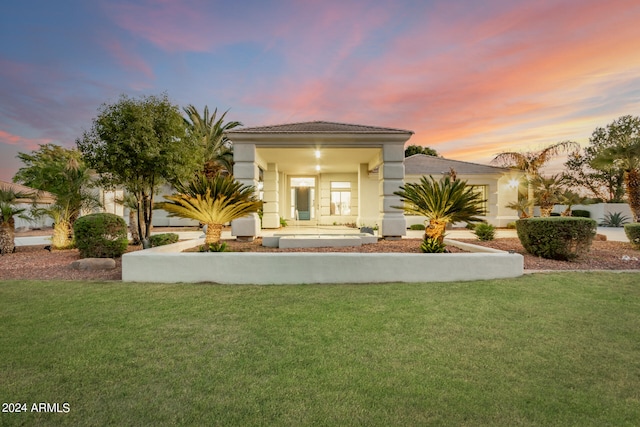 back house at dusk featuring a yard