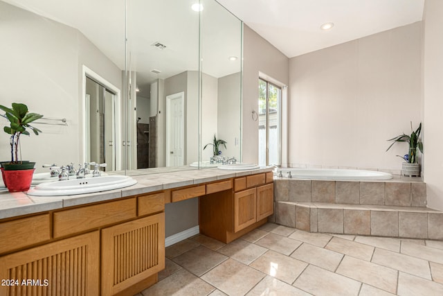 bathroom featuring a relaxing tiled tub, tile patterned floors, and vanity