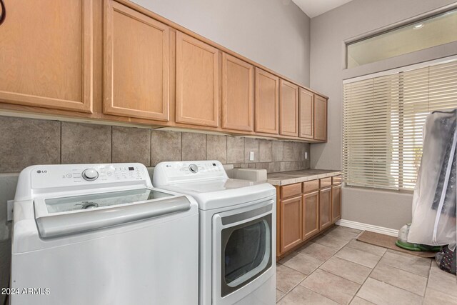 washroom with cabinets, light tile patterned flooring, and washing machine and dryer