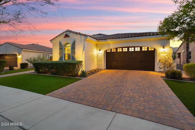 mediterranean / spanish-style home with a lawn and a garage