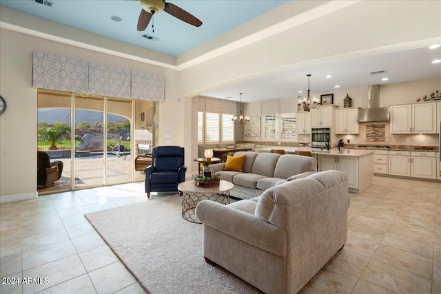 tiled living room with ceiling fan with notable chandelier