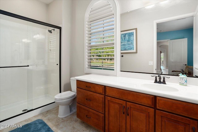 bathroom with a shower with shower door, vanity, and toilet