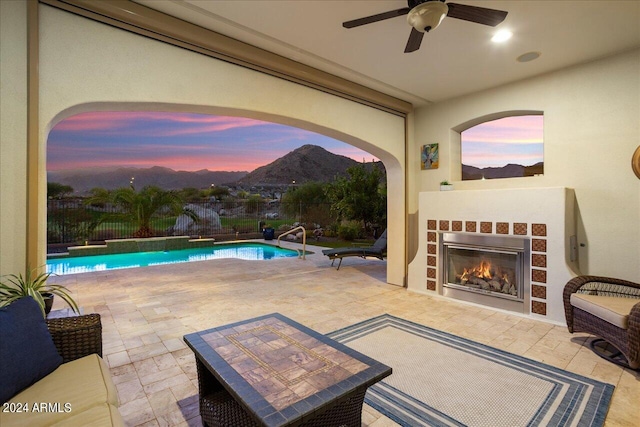 exterior space featuring exterior fireplace, a mountain view, a fenced in pool, and ceiling fan