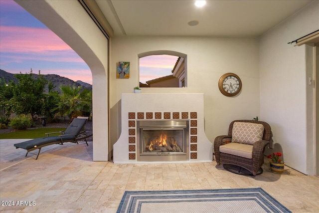 patio terrace at dusk featuring a mountain view and exterior fireplace