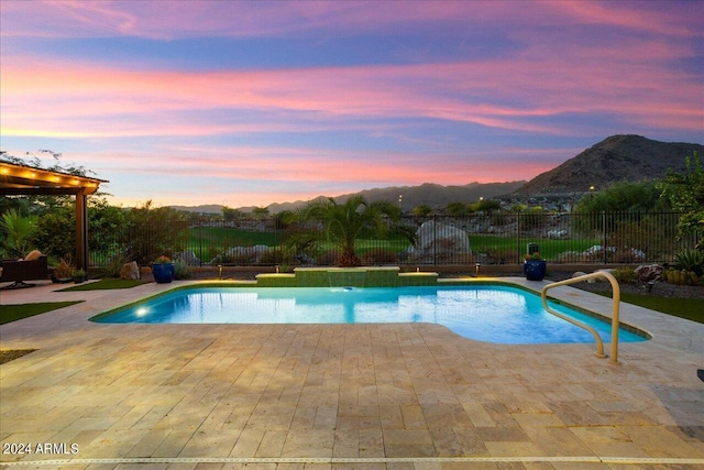 pool at dusk featuring a mountain view and a patio