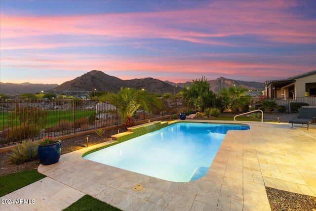 pool at dusk featuring a patio area and a mountain view