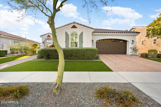 mediterranean / spanish house with a garage and a front lawn