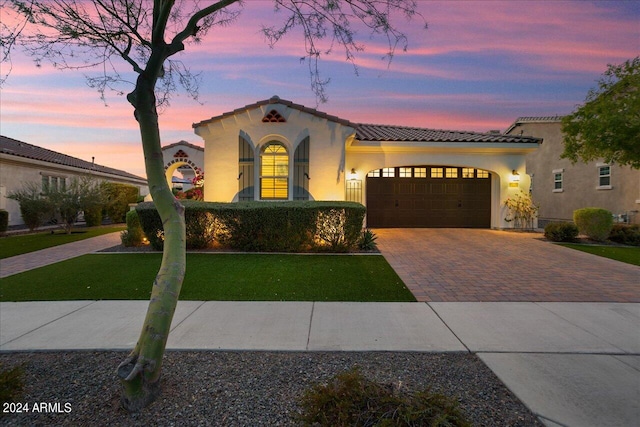 mediterranean / spanish-style home with a yard and a garage