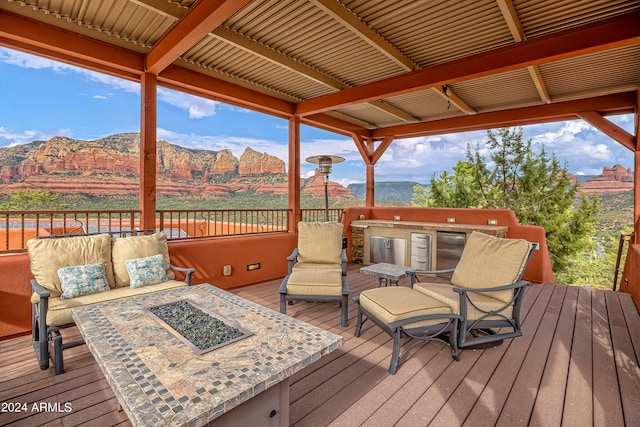 deck featuring a mountain view and an outdoor living space with a fire pit