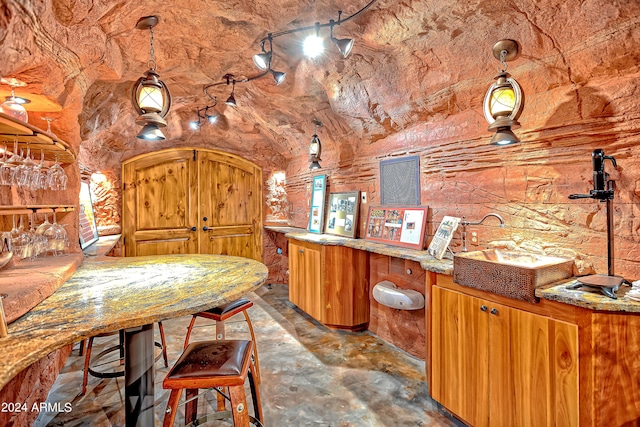 interior space with hanging light fixtures, light stone countertops, and lofted ceiling