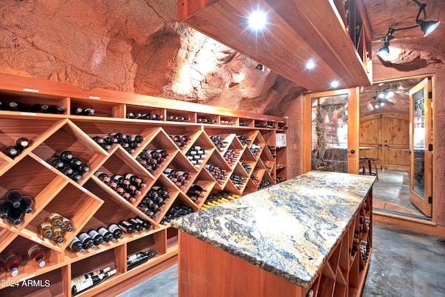 wine room with concrete flooring and vaulted ceiling