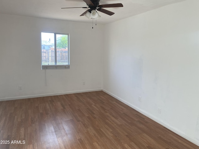 empty room featuring wood finished floors, a ceiling fan, and baseboards