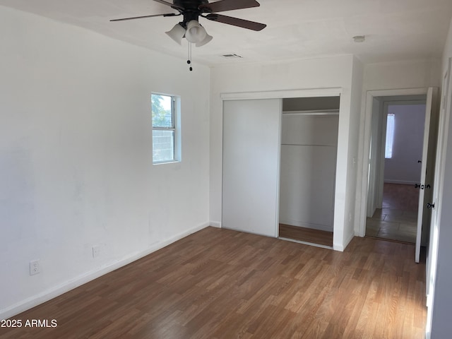 unfurnished bedroom featuring a closet, wood finished floors, baseboards, and a ceiling fan