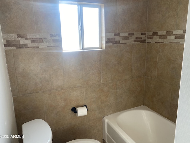 bathroom with toilet, a bath, and tile walls