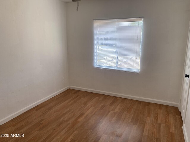 empty room featuring wood finished floors and baseboards
