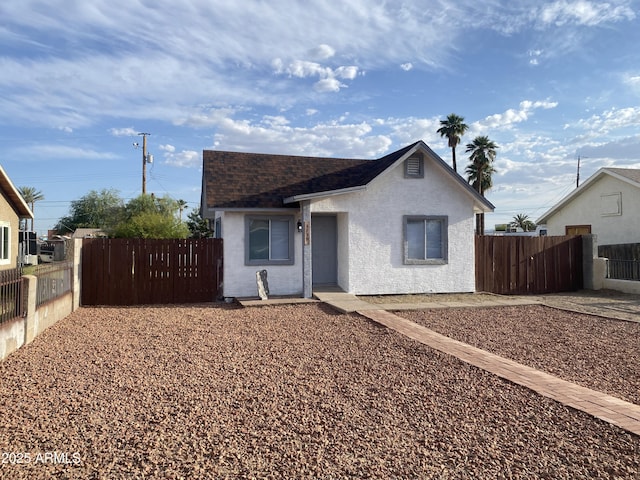 bungalow with fence, a shingled roof, and stucco siding