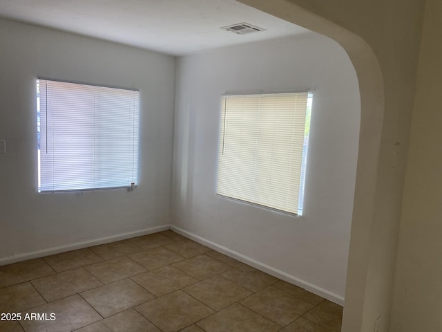 tiled empty room with arched walkways and baseboards