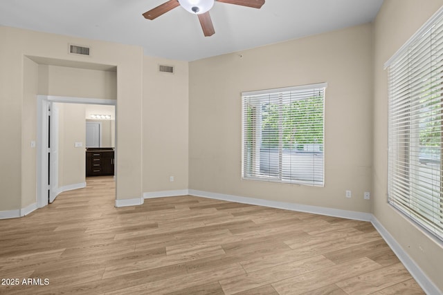 unfurnished room with visible vents, a ceiling fan, light wood finished floors, and baseboards