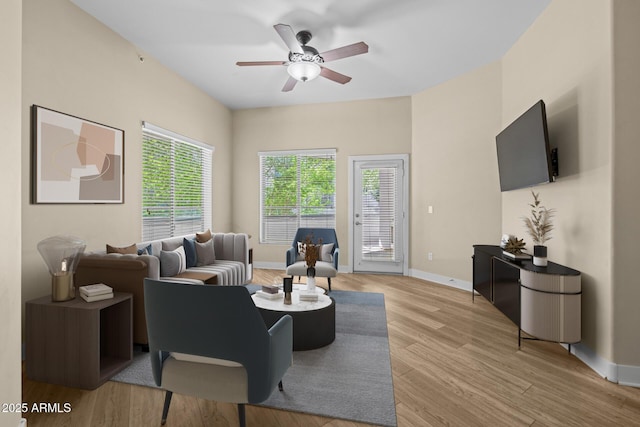 living area with baseboards, ceiling fan, and light wood-style flooring