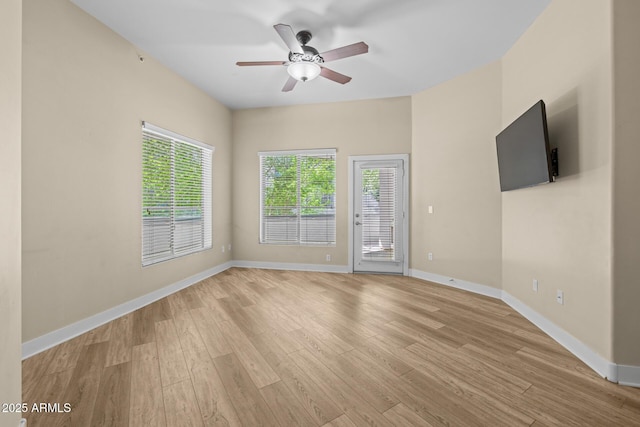 empty room featuring baseboards, a ceiling fan, and light wood finished floors