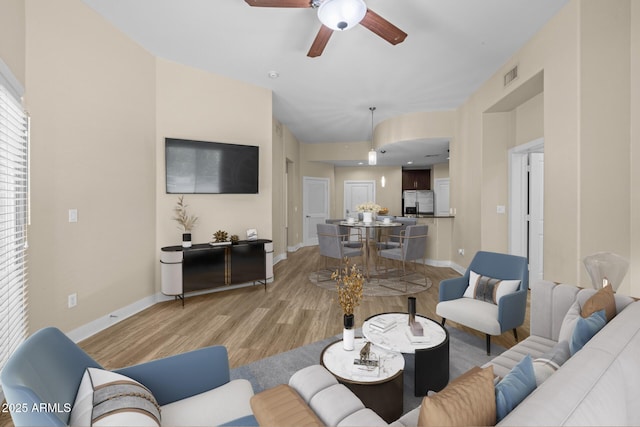 living area featuring visible vents, a ceiling fan, light wood finished floors, and baseboards