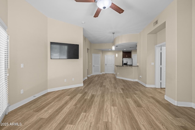 unfurnished living room with visible vents, light wood-style flooring, ceiling fan, and baseboards