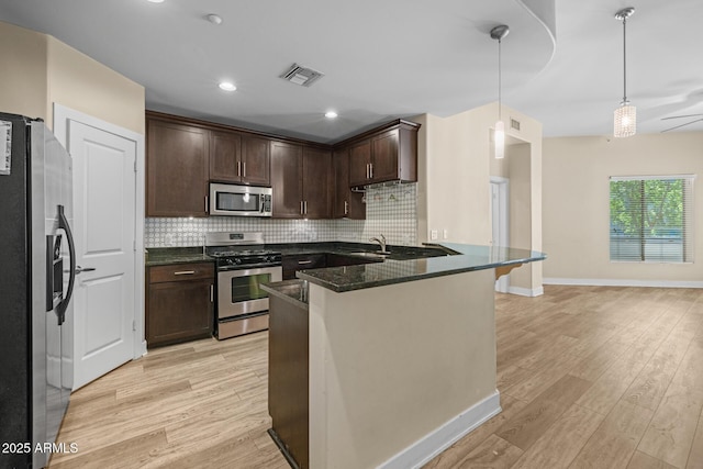 kitchen with light wood-style floors, tasteful backsplash, stainless steel appliances, and visible vents