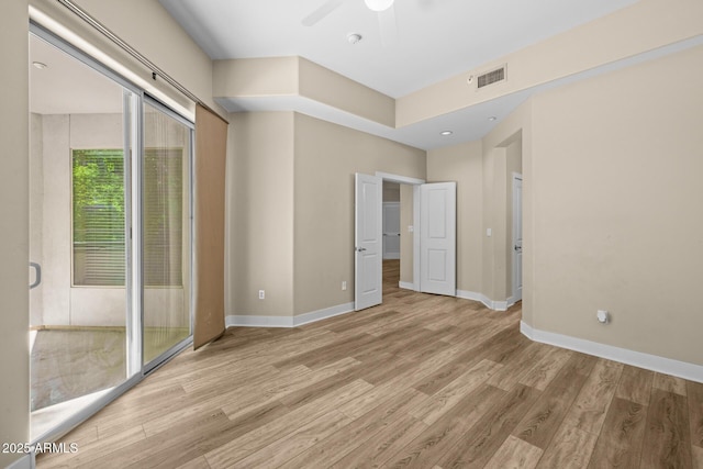 empty room featuring visible vents, light wood-style floors, and baseboards