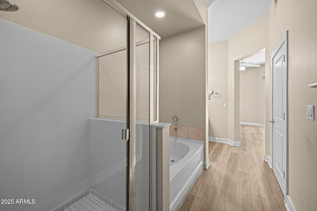 bathroom featuring a stall shower, recessed lighting, a bath, and wood finished floors