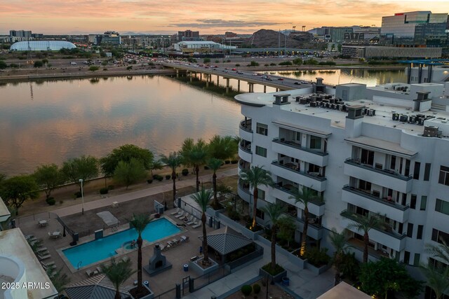 aerial view at dusk featuring a water view and a city view