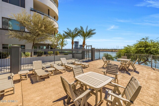 view of patio with a water view, fence, and outdoor dining area