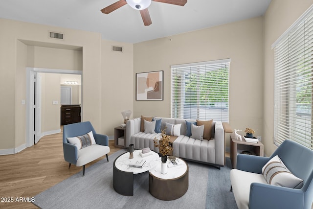 living room with baseboards, a ceiling fan, wood finished floors, and visible vents