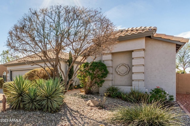 view of front of home featuring a tile roof, fence, and stucco siding