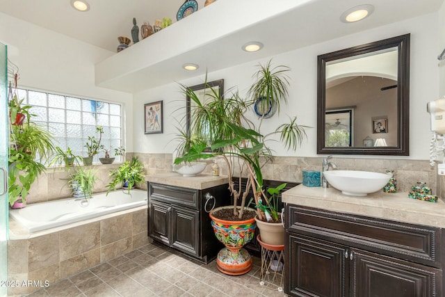 full bathroom featuring a garden tub, two vanities, a sink, and recessed lighting