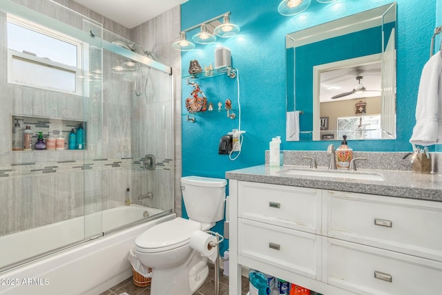 full bathroom with bath / shower combo with glass door, a textured wall, toilet, tile patterned flooring, and vanity