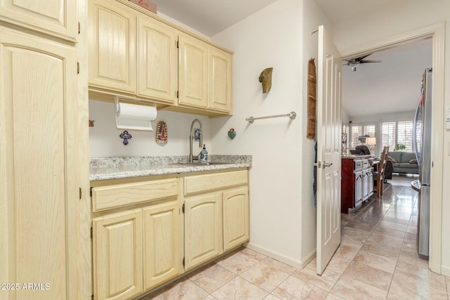 kitchen featuring ceiling fan, baseboards, a sink, and freestanding refrigerator