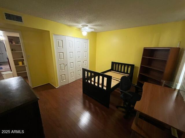 bedroom featuring a closet, dark hardwood / wood-style floors, a textured ceiling, and ceiling fan