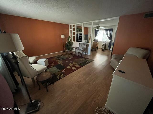 living room with wood-type flooring, ceiling fan, and a textured ceiling