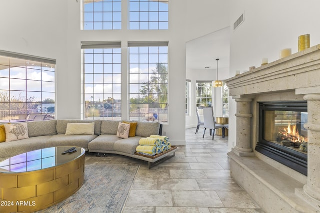 living room with a high end fireplace, a wealth of natural light, and a high ceiling