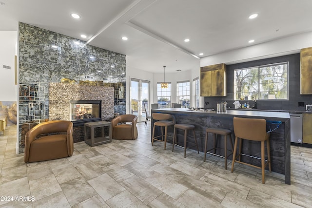 kitchen featuring a tile fireplace, a kitchen breakfast bar, dishwasher, and sink