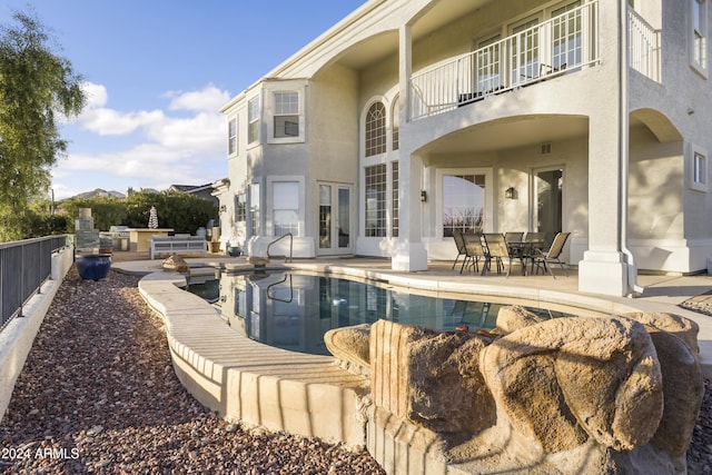 back of house with a patio area, a balcony, exterior kitchen, and a fenced in pool