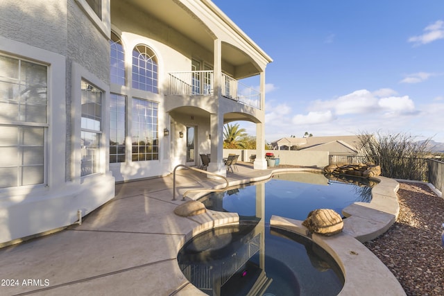 view of patio / terrace featuring a swimming pool with hot tub and a balcony