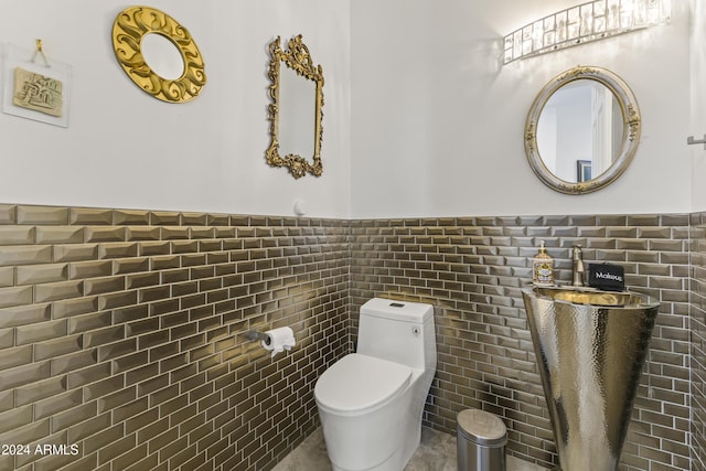 bathroom featuring toilet and tile walls