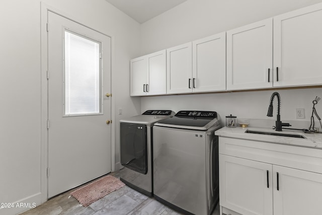 laundry area with cabinets, light wood-type flooring, washing machine and dryer, and sink