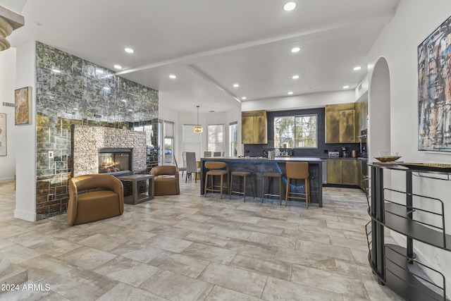 interior space featuring a kitchen bar, a stone fireplace, and double oven