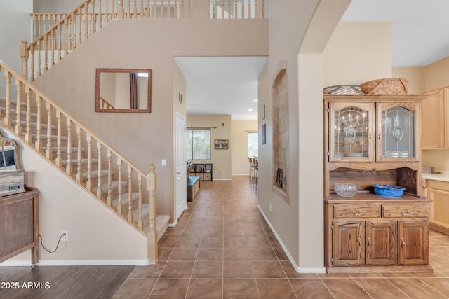 entrance foyer featuring tile patterned floors, stairway, baseboards, and arched walkways