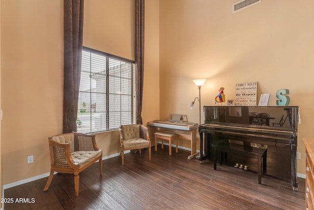 living area featuring visible vents, baseboards, and wood finished floors