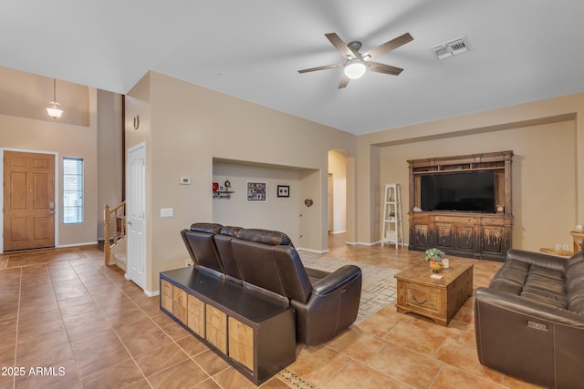 living room featuring visible vents, a ceiling fan, arched walkways, light tile patterned floors, and baseboards