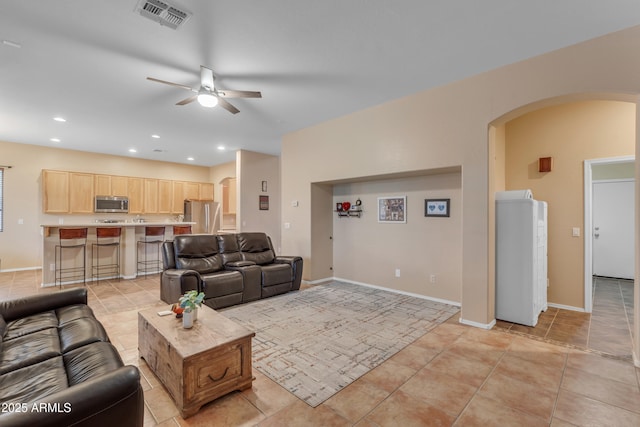 living area featuring visible vents, light tile patterned floors, recessed lighting, arched walkways, and a ceiling fan