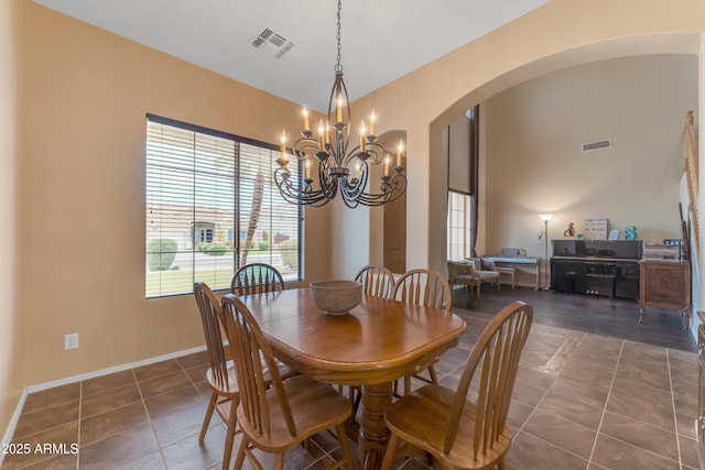 tiled dining area with an inviting chandelier, arched walkways, visible vents, and baseboards